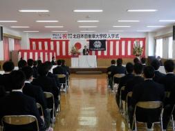 北日本自動車大学校入学式で壇上で市長が語っている様子。